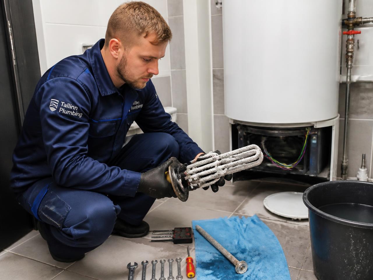 Boileri puhastus Tallinnas — Toru SOS OÜ torumees eemaldab elektriboilerist katlakiviga kaetud küttekeha ja magneesiumanoodi
